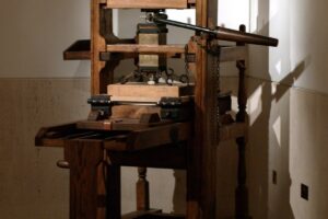 An old wooden hand printing press standing in warm window light