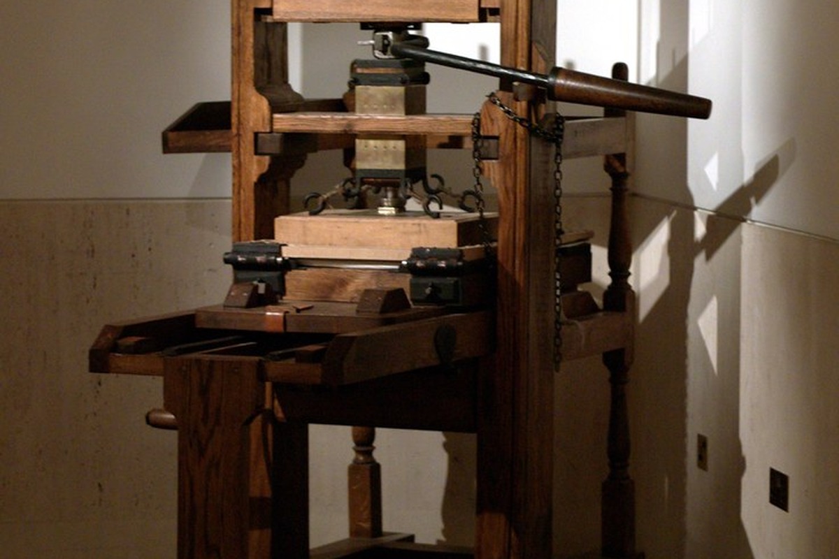 An old wooden hand printing press standing in warm window light